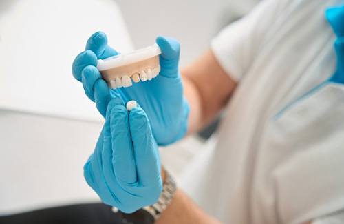 Dentist pulling a dental crown from model teeth