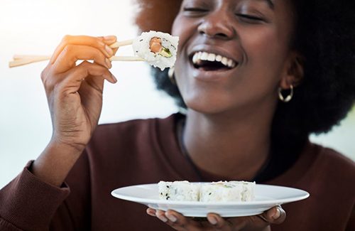 Woman smiling as she eats sushi 