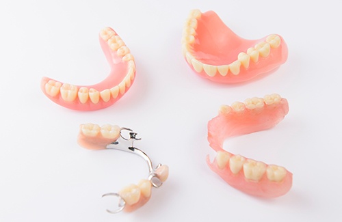 Full and partial dentures arranged in a circle on a white surface