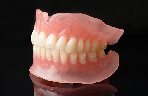 Full set of dentures on reflective black surface