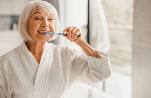 an older woman brushing her teeth in the morning