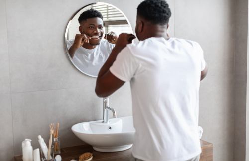 Man smiling while flossing in bathroom