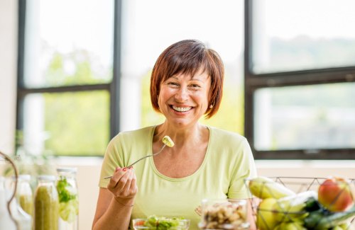 Woman smiling while eating healthy meal at home