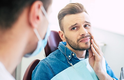 Man with toothache looking at dentist during exam